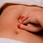 A soothing massage on a woman's abdomen with painted nails, creating a serene spa atmosphere.